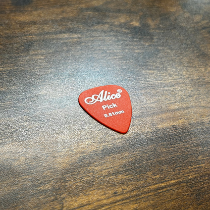 Dark Orange guitar pick with 'Alice' branding on a wooden surface
