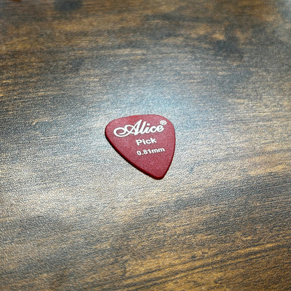 Alice 0.81mm guitar pick on a wooden desk in a bright background