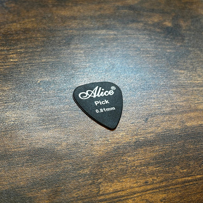 Black 0.81mm guitar pick with 'Alice' branding on a wooden surface