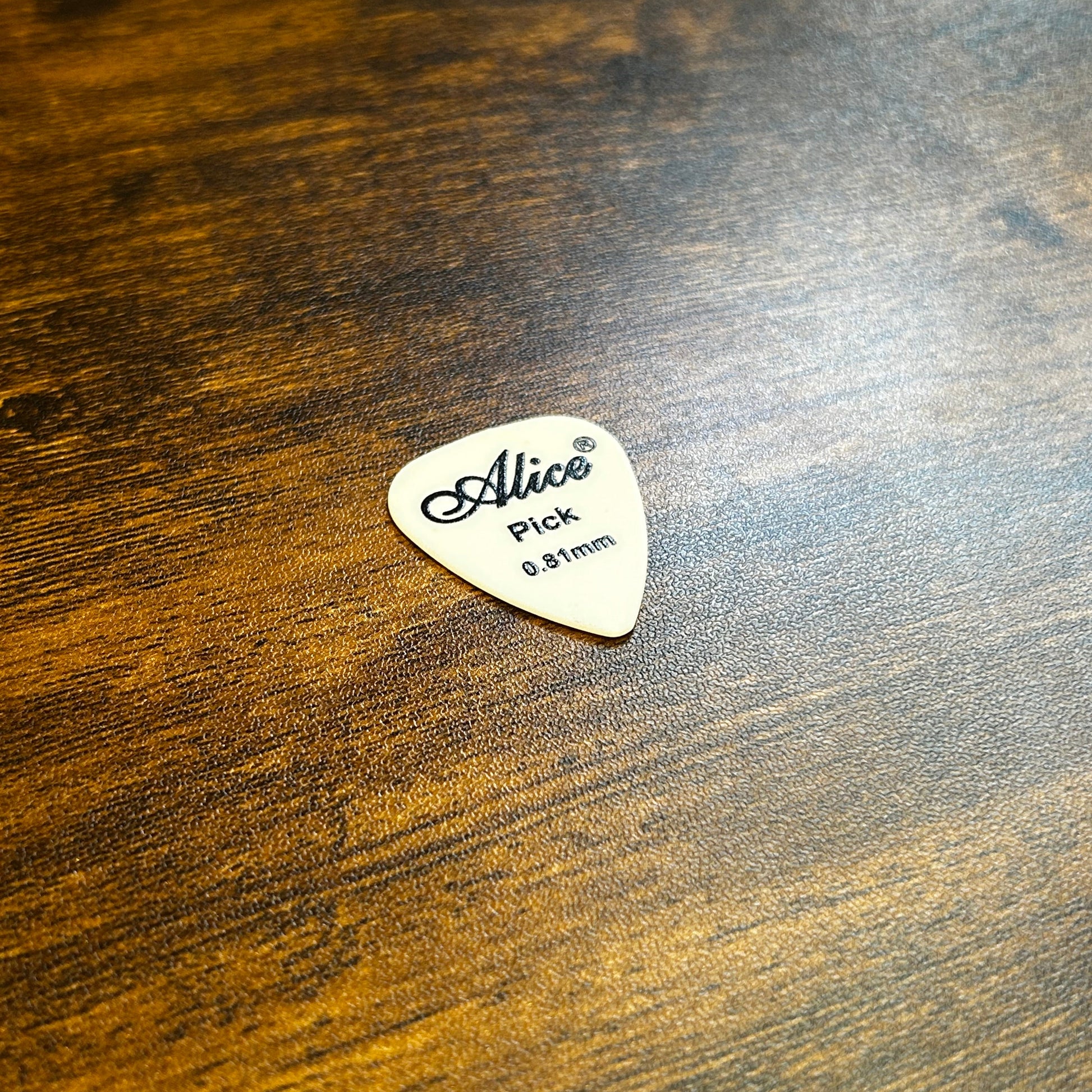 White 0.81mm Alice Guitar Pick on  a wooden surface